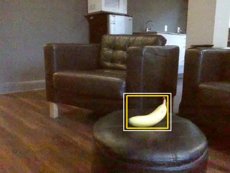 Tello camera frame of a banana on a footstool, with the YOLO bounding box and the padded crop box drawn around it